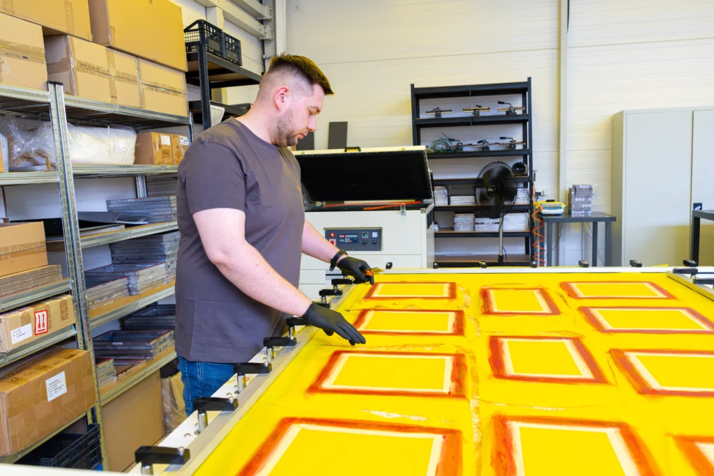 Pracownik Działu Opracowania Grafiki i Wykonania Sit przy przygotowaniu sit do sitodruku